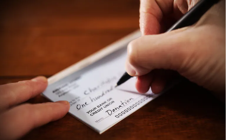 Photo of a hand writing a check