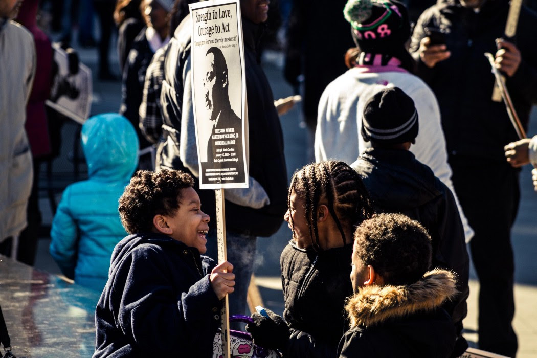 Crowd of people with person holding up poster of Martin Luther King Junior