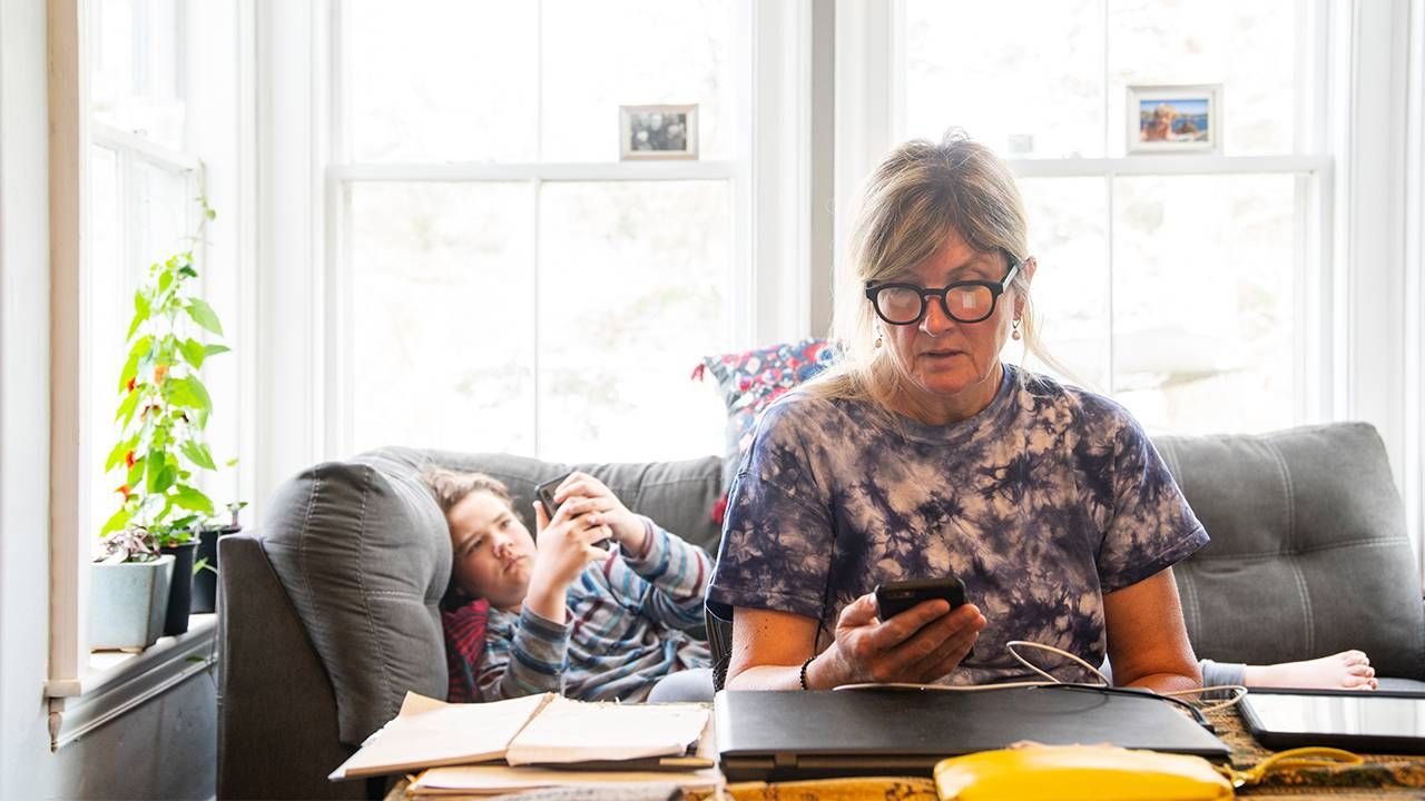 woman workind at desk. Child on couch begin her.