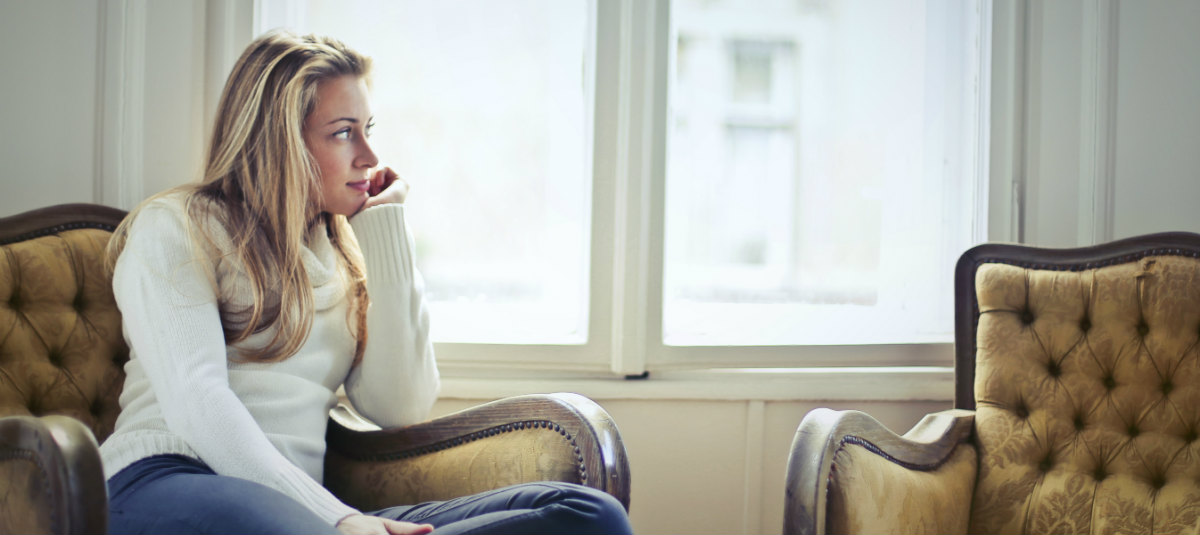 woman sitting on coach and resting her head in her hand